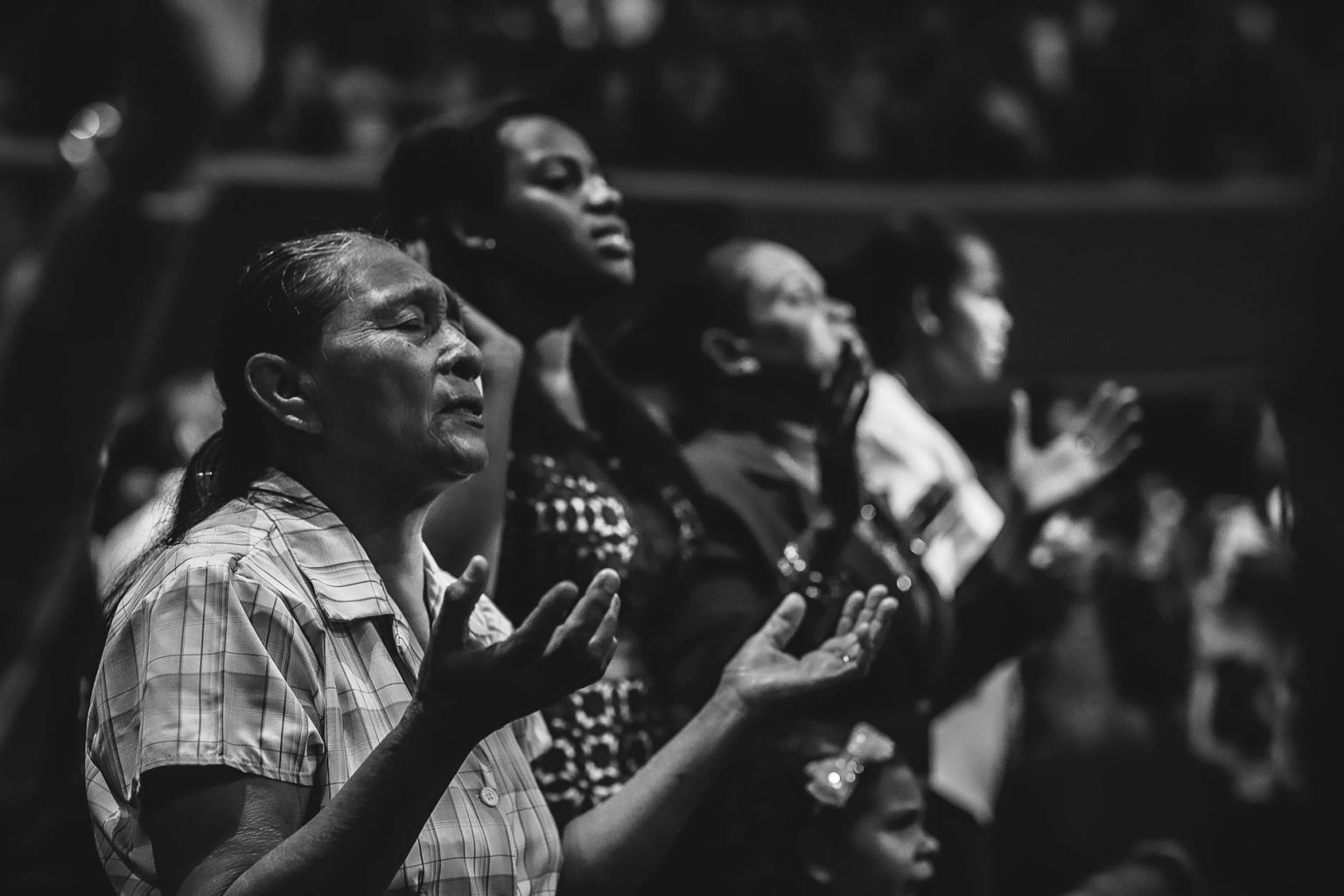 grayscale photo of people raising hands